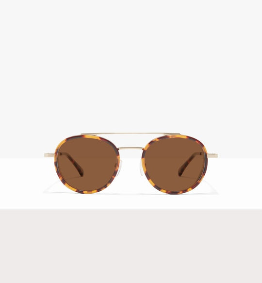 Tortoiseshell sunglasses with round brown lenses and thin gold temples against a neutral background.